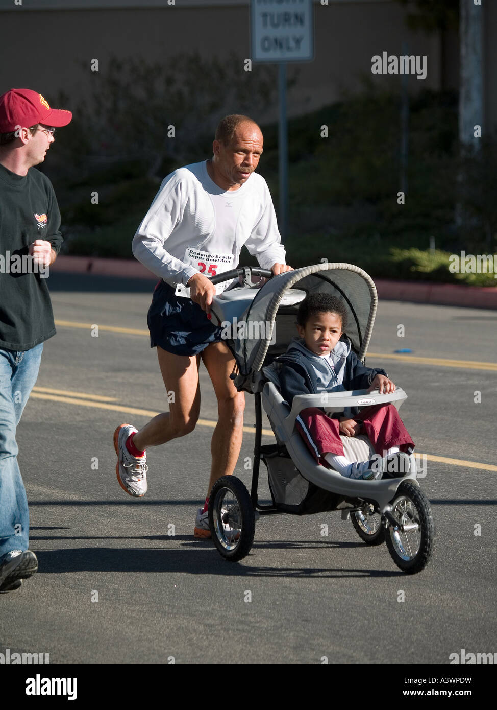 Schwarzer Mann mit Mudigkeit schiebt jungen Sohn Baby Buggy Wettbewerb. Redondo Beach CA. Superschussel Sonntag 10K USA Stockfotografie Alamy