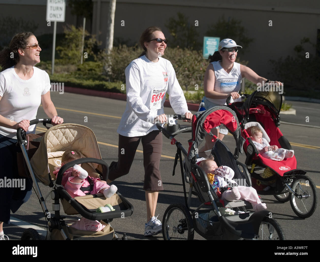 Drei glückliche junge weiße Frauen schieben ihre Babys im Kinderwagen in  Redondo Beach CA. Super Bowl Sonntag 10K Stockfotografie - Alamy
