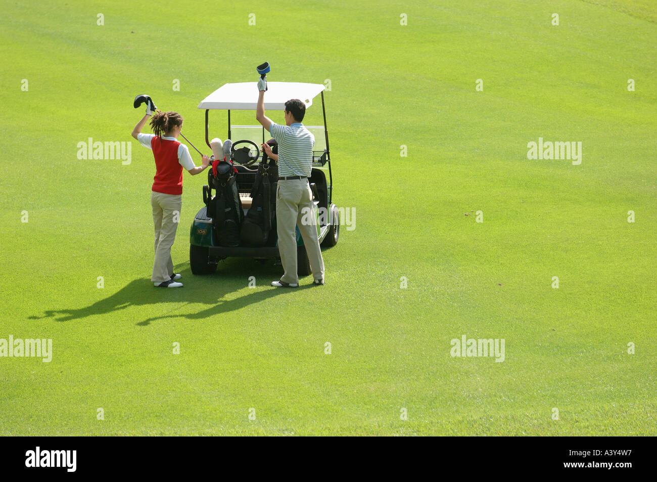 Paar unter Clubs aus einem Golf-Cart Stockfoto