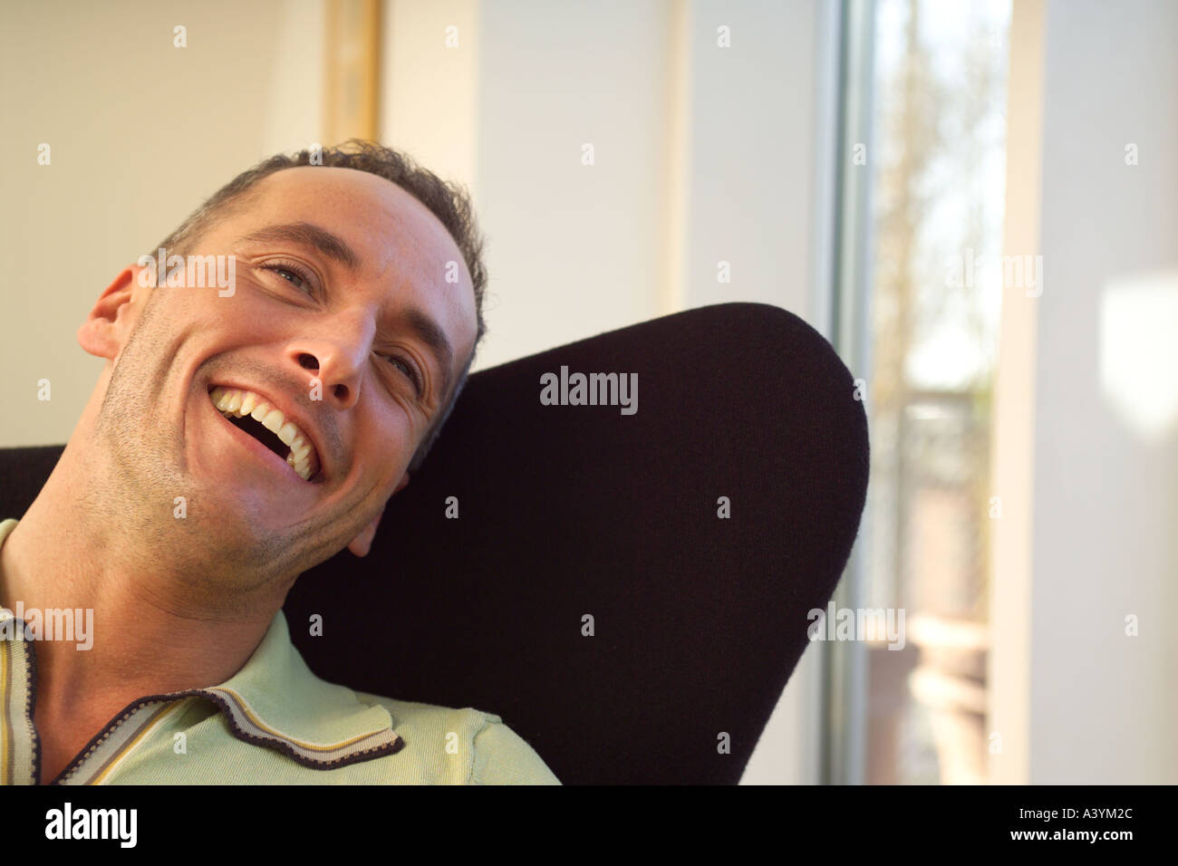jungen Mann Lachen in schwarz Sessel Stockfoto