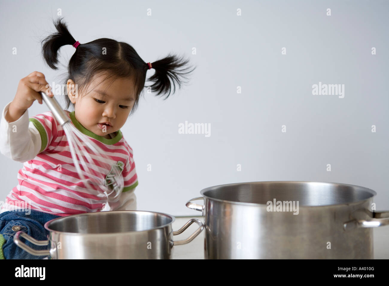 Asiatisches Baby Spiel mit Quirl und Kochtöpfe Stockfoto