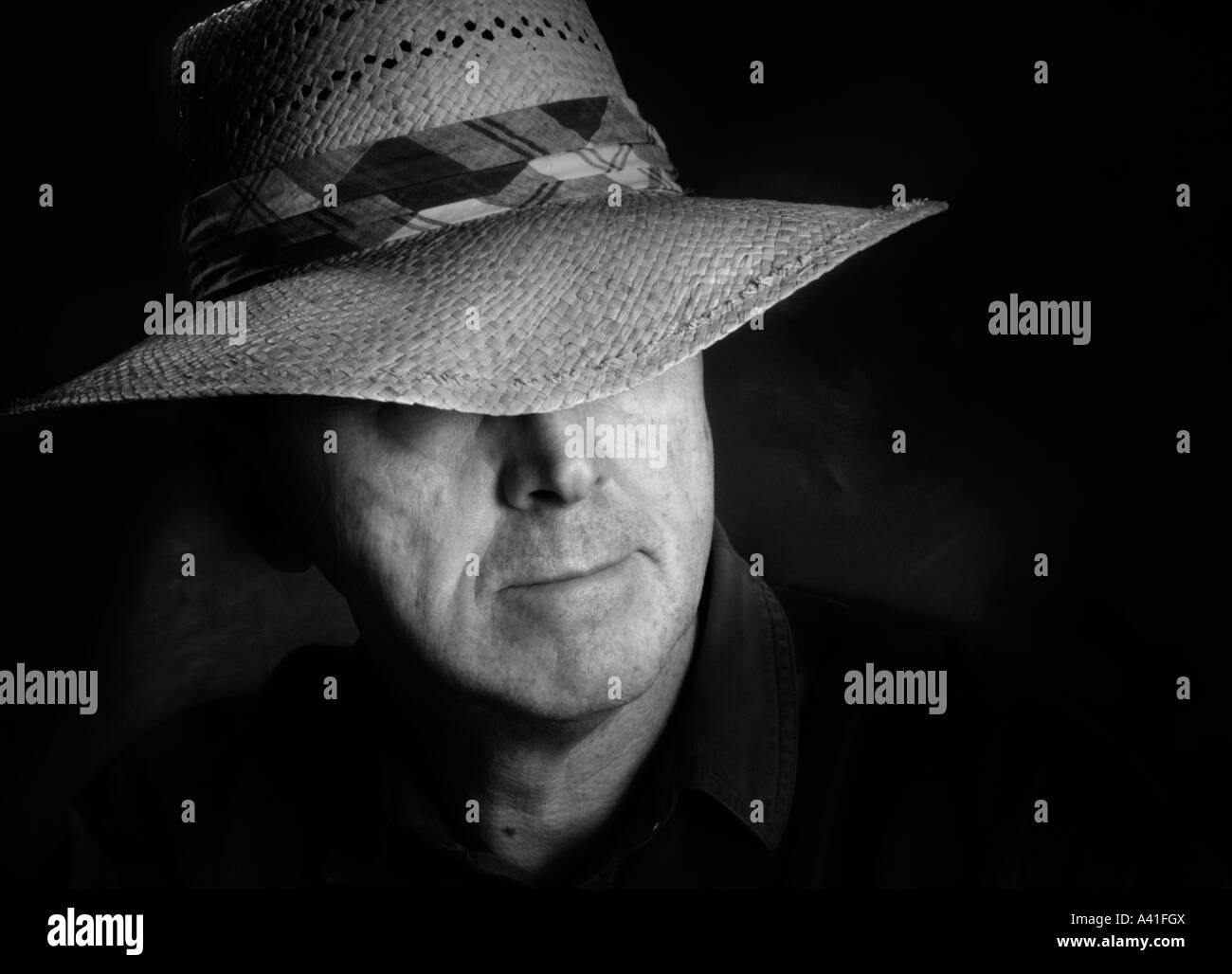 Porträt eines Mannes in einem Strohhut, der einen karierten Hutband hat.  Schwarz / weiß-version Stockfoto