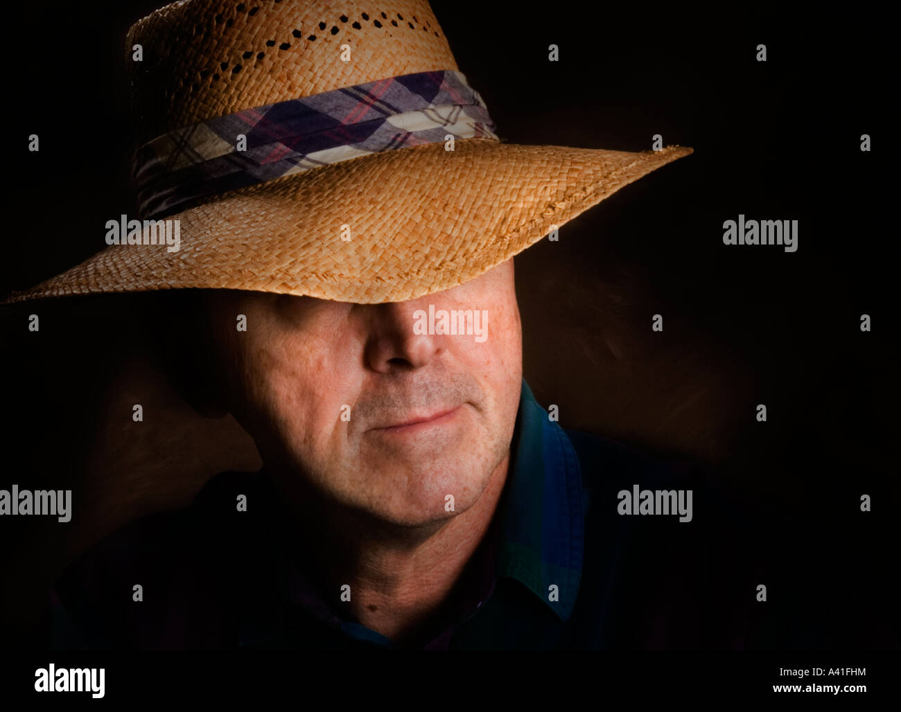 Porträt eines Mannes in einem Strohhut, der einen karierten Hutband hat Stockfoto