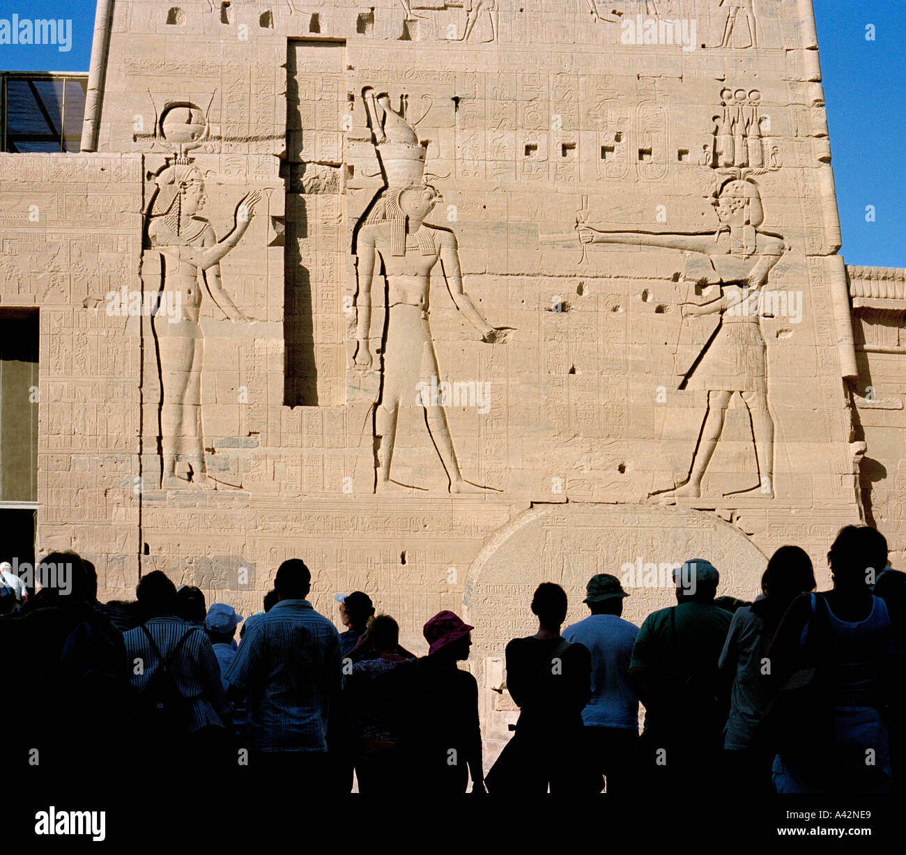 Touristen, die Silhouette gegen Stiche von den Göttern an einem Hochspannungsmast am Tempel der Isis in Philae Stockfoto