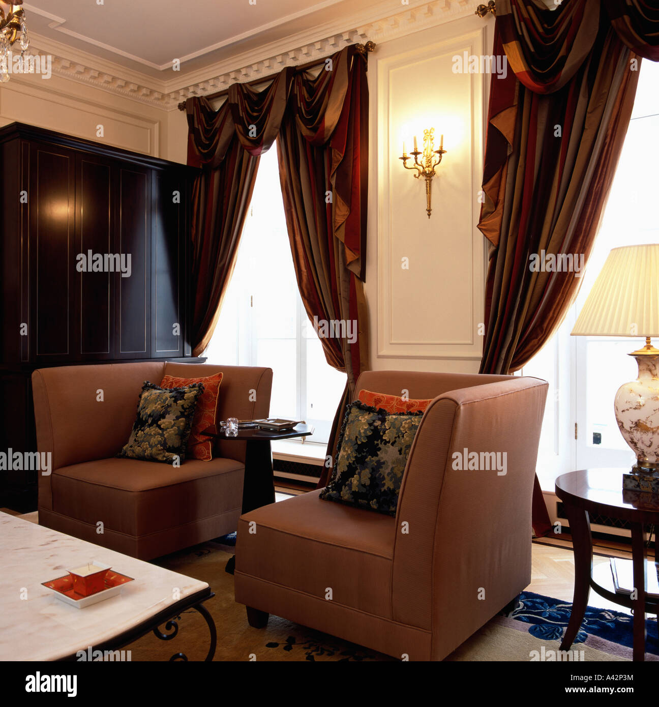 Ecke Sessel und schwere braune Seide Vorhänge auf hohen Fenster im Salon Stadthaus Stockfoto