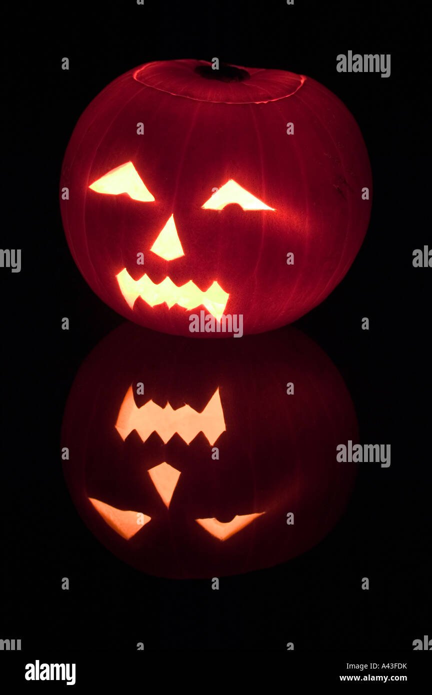 Ein gruselige Halloween-Kürbis mit Kerze von innen gegen einen schwarzen Hintergrund mit Reflexion beleuchtet Stockfoto