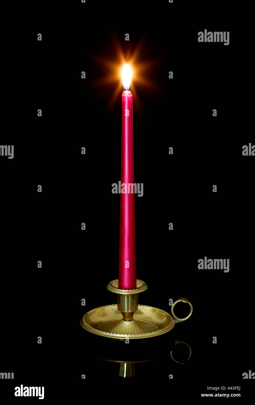 Rote Kerze brennen in einen Messing Kerzenständer vor einem schwarzen Hintergrund mit Reflexion Stockfoto