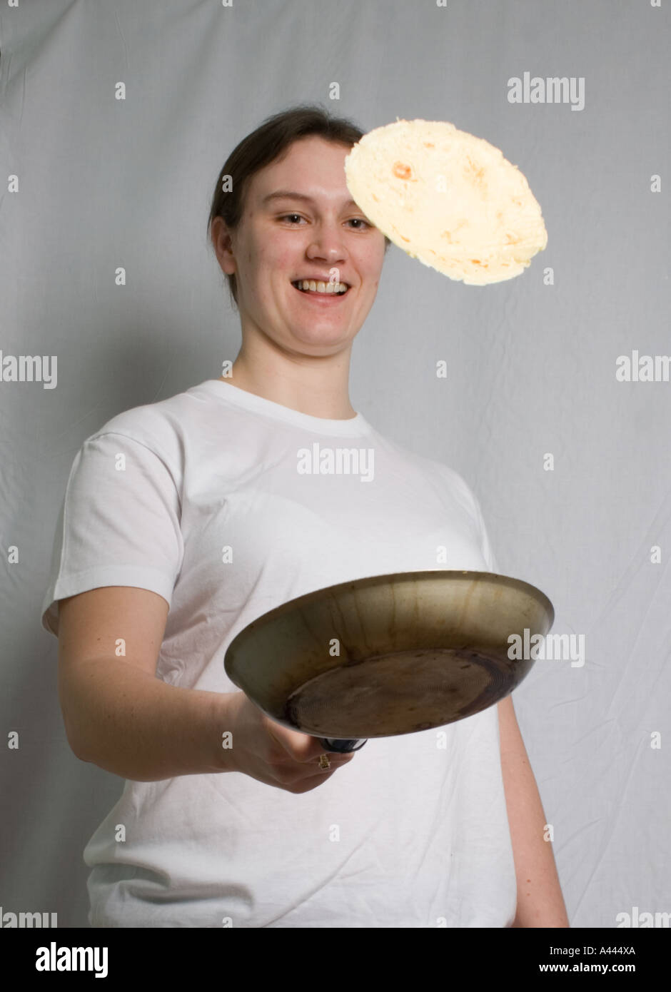 junge Frau warf einen Pfannkuchen Stockfoto