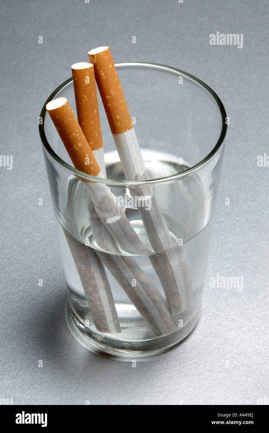 Zigaretten in einem Glas Wasser Stockfoto