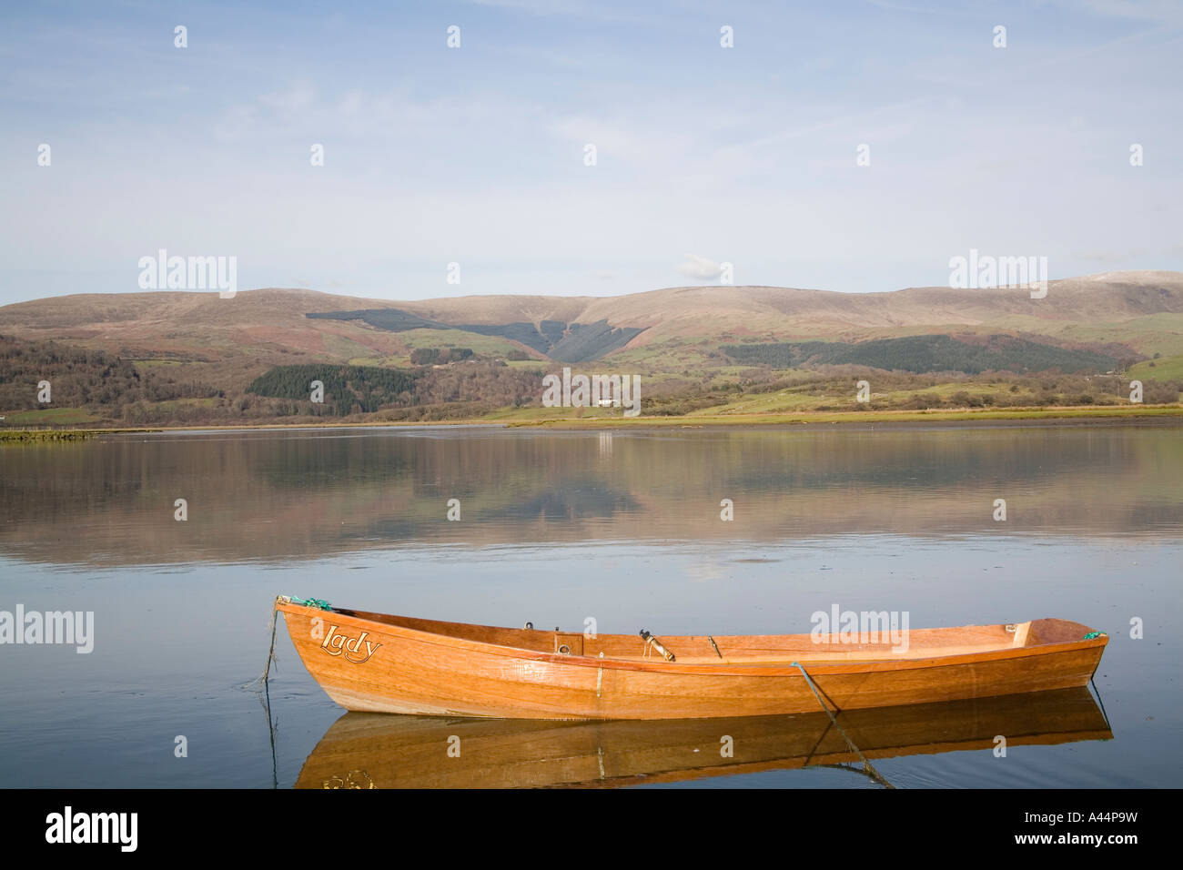 GLANDYFI CEREDIGION MID WALES UK Januar eine braune Ruderboot an der Seite des sehr breiten noch River Dovey festgemacht ist Stockfoto