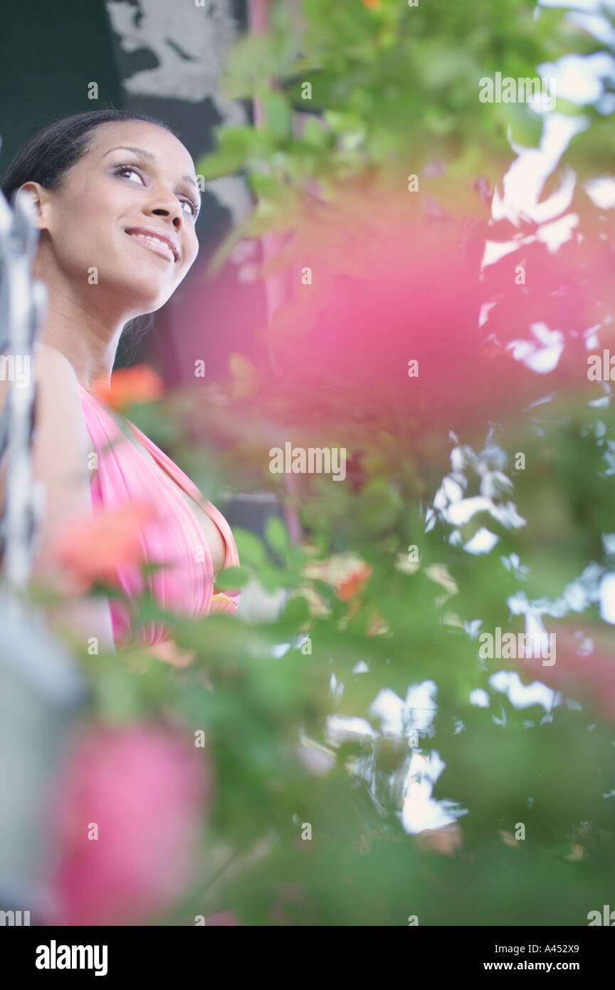 Junge Frau stand hinter Pflanzen Stockfoto