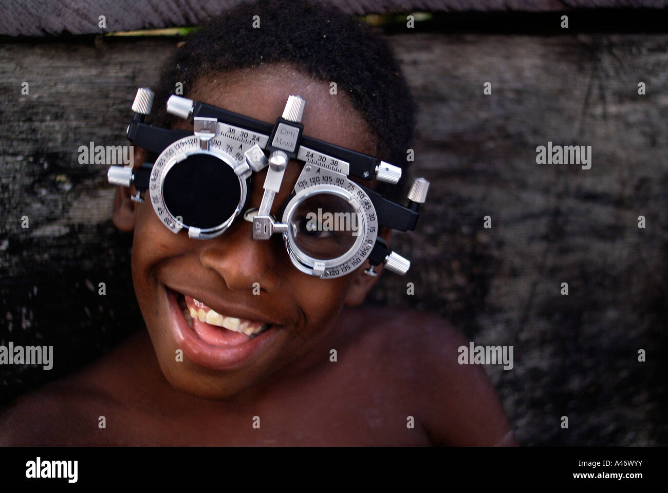 Lachender Junge mit einem Instrument für Augenuntersuchungen in Imbiribeira Slum (Favela), Recife, Brasilien Stockfoto