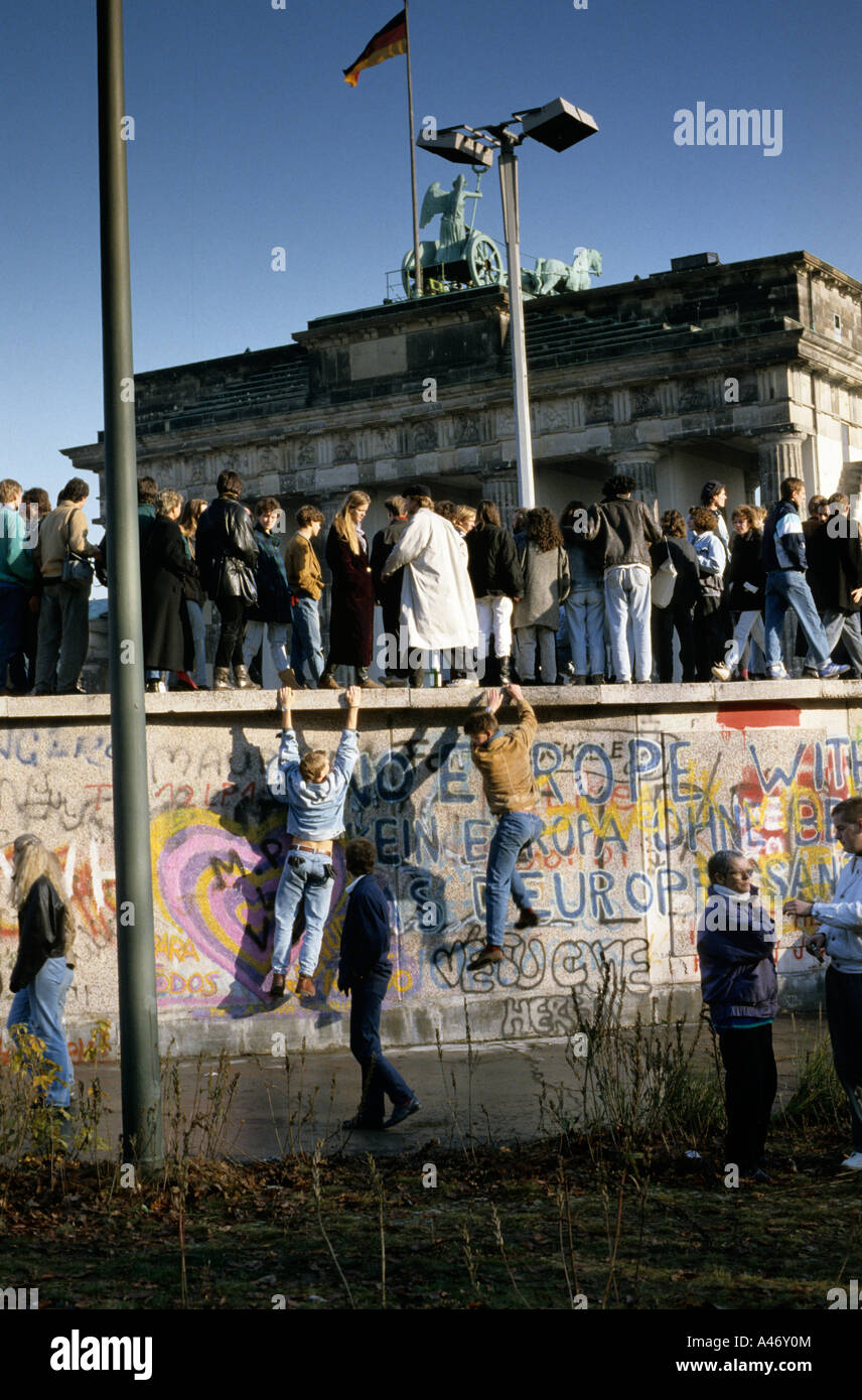 Fall der Berliner Mauer: Menschen aus Ost und West-Berliner Klettern an der Wand vor dem Brandenburger Tor, Berlin, Deutschland Stockfoto