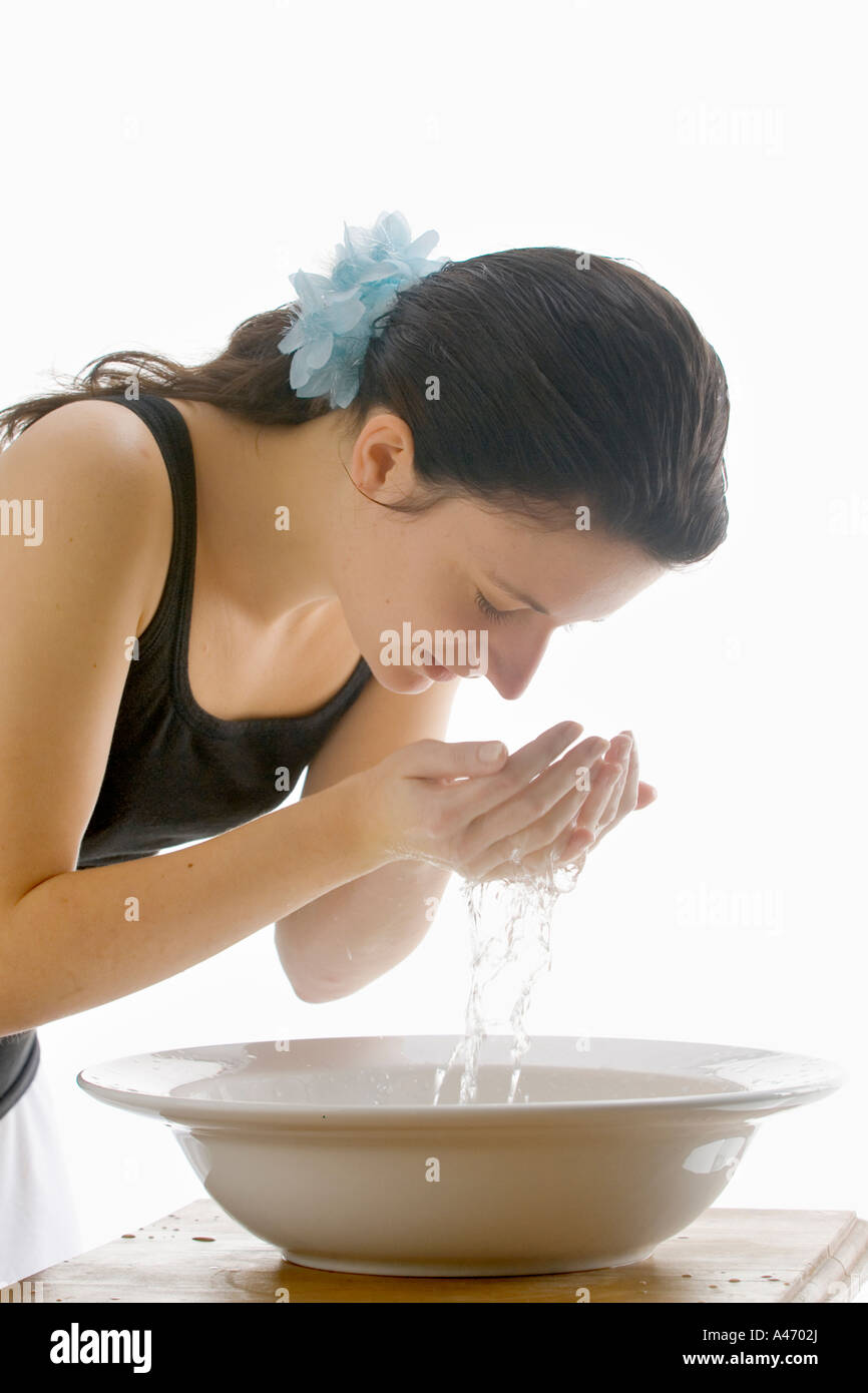 Junge Frau nimmt Wasser aus einer Waschschüssel Stockfoto