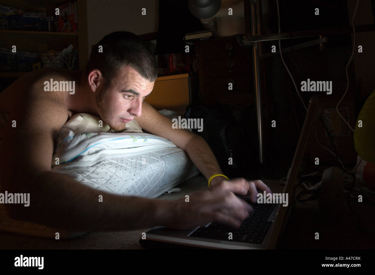 Junger Mann liegend im verdunkelten Zimmer und arbeiten auf Laptop-Computer. Stockfoto