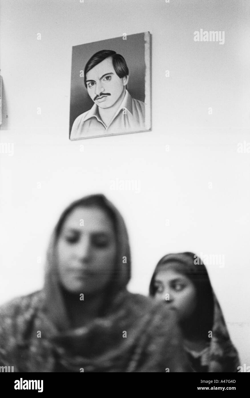eine Frau und ihre Tochter unter ein Porträt ihres Ehemannes durch orthodoxe sunnitische Muslime getötet Stockfoto