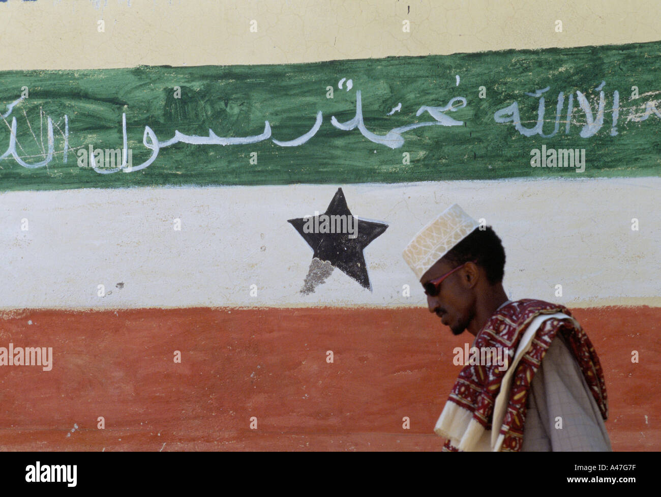 ein Mann geht Vergangenheit eine bemalte Fahne des selbst unabhängigen Somaliland in der Bruoa Stadt angemeldet Stockfoto