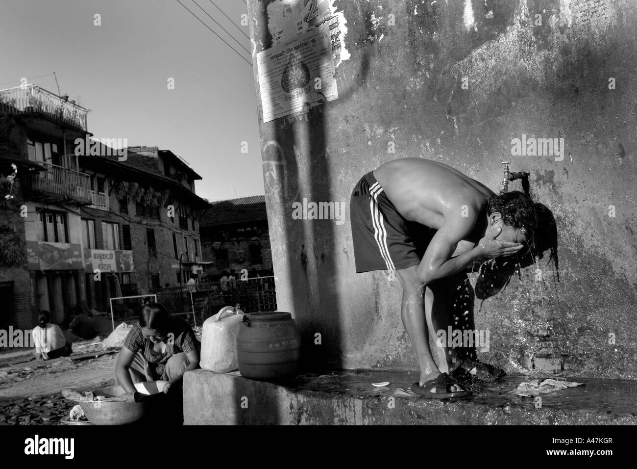 Ein Mann nimmt eine Dusche auf der Straße das ländliche Dorf Bungamati außerhalb von Kathmandu in Nepal Stockfoto