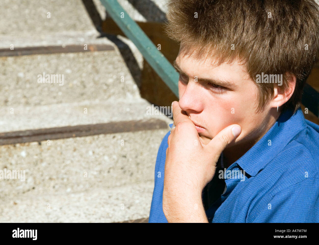 Porträt von nachdenklich kaukasischen Teenager sitzen auf Stufen. Er hat einen sehr nachdenklichen Blick auf seinem Gesicht. Stockfoto