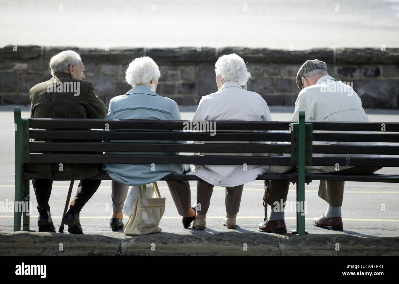 Ältere Menschen sitzen auf einer Bank am Meer in Weston-Super-Mare in Somerset UK Stockfoto