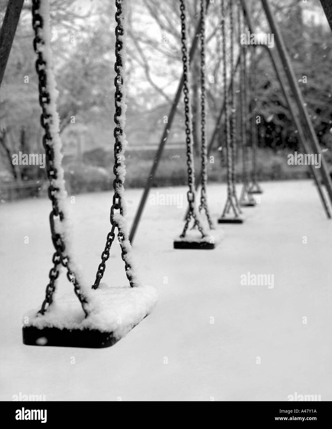 Eine ungewöhnliche London Park Szene nach eine Prise Winterschnee zeigt eine Reihe von Schaukelsitze mit Schnee bedeckt Stockfoto