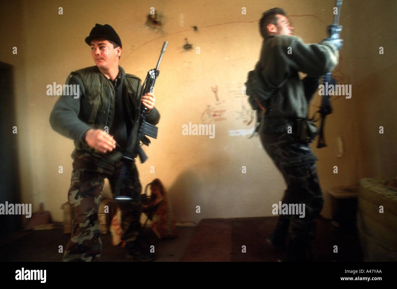 Zwei kroatische Soldaten laufen für Deckel, wie sie unter Beschuss in einem verlassenen Haus in Sunja, Kroatien, Jugoslawien kommen Stockfoto