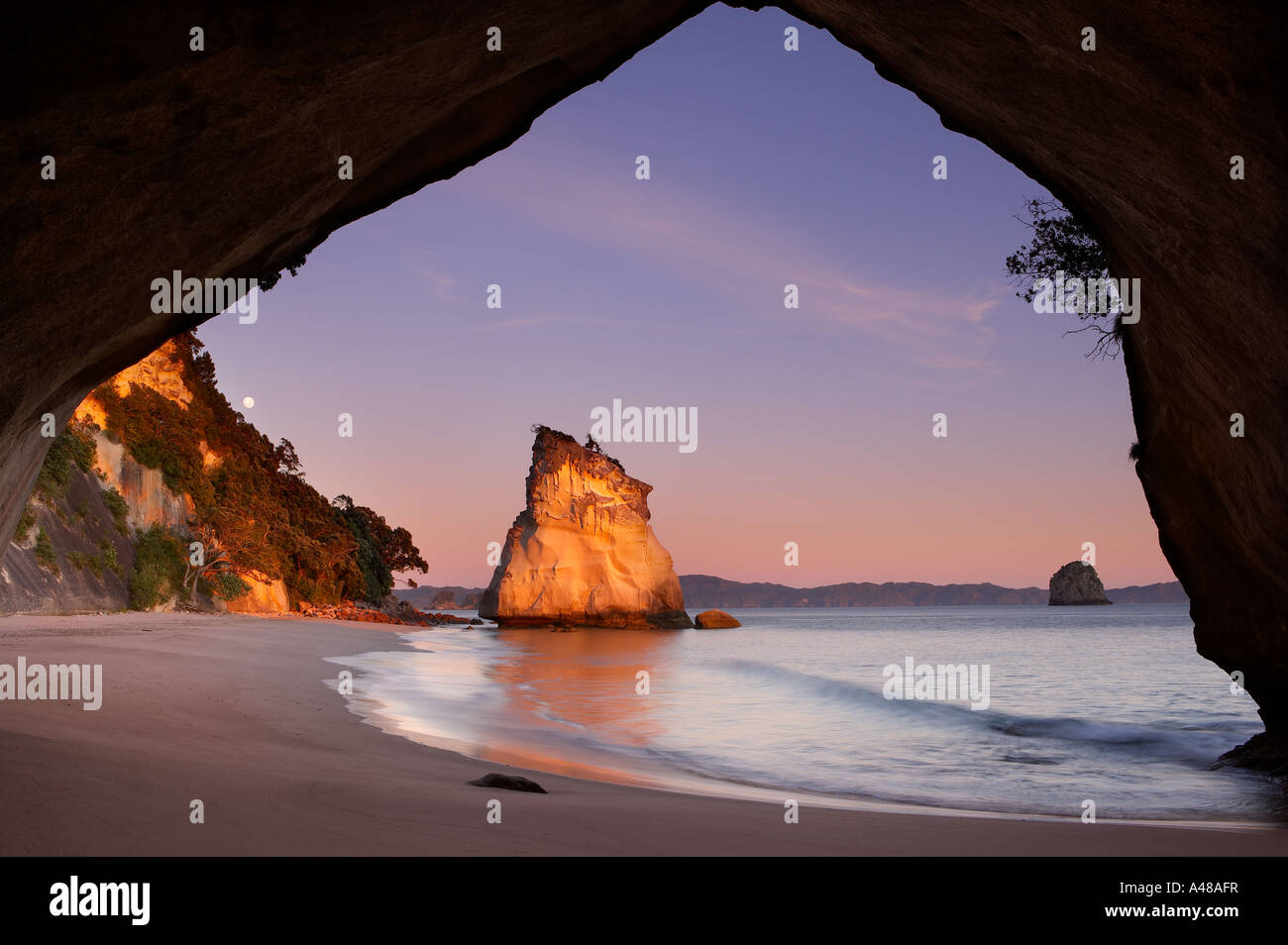 der Mond über Cathedral Cove im Morgengrauen nr Hahei Coromandel Halbinsel North Island Neuseeland NR Stockfoto