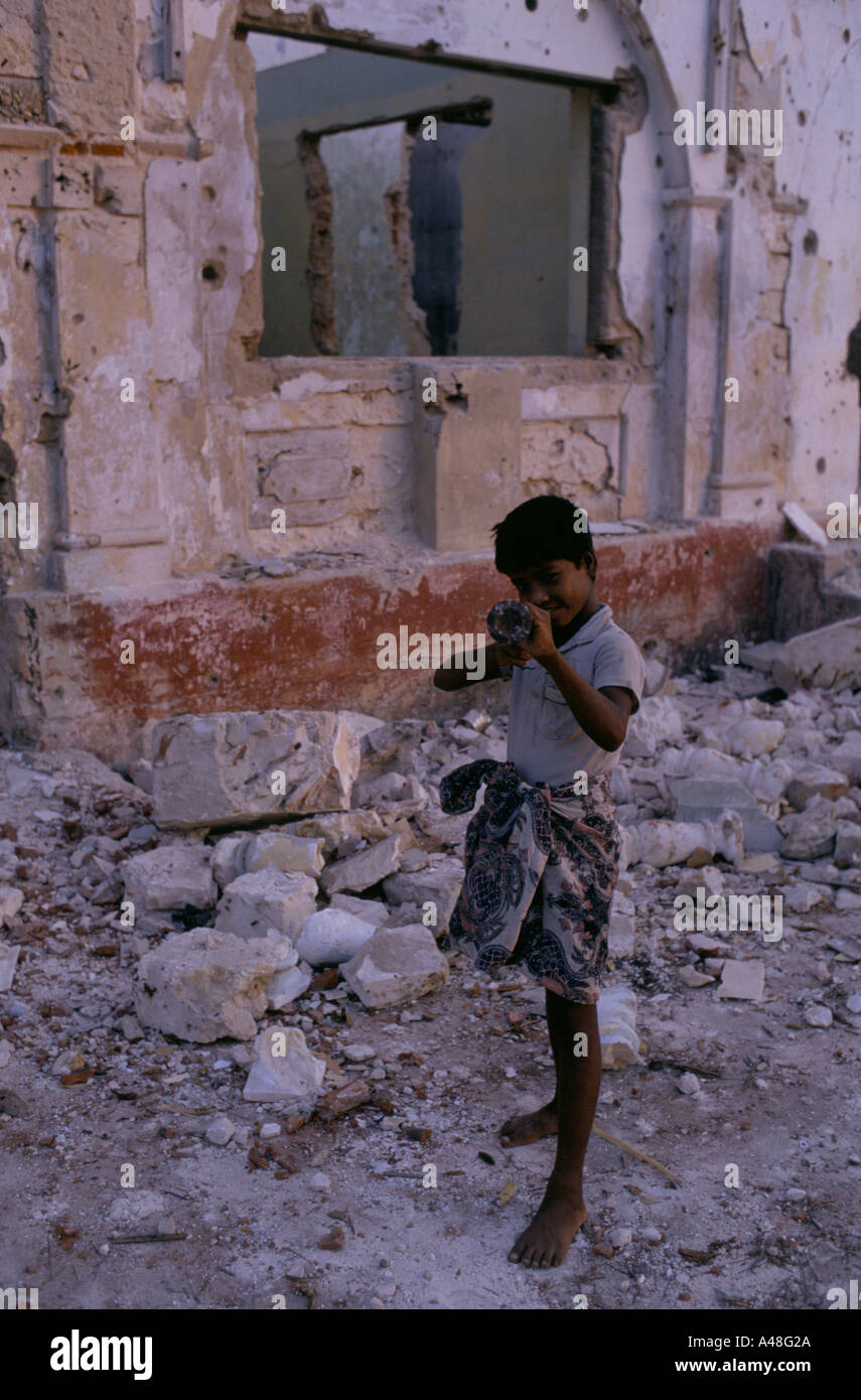 Ein Tamil Kind ausspielen Kriegsspiele neben dem zerbombten Ruinen der Häuser in Jaffna Stockfoto