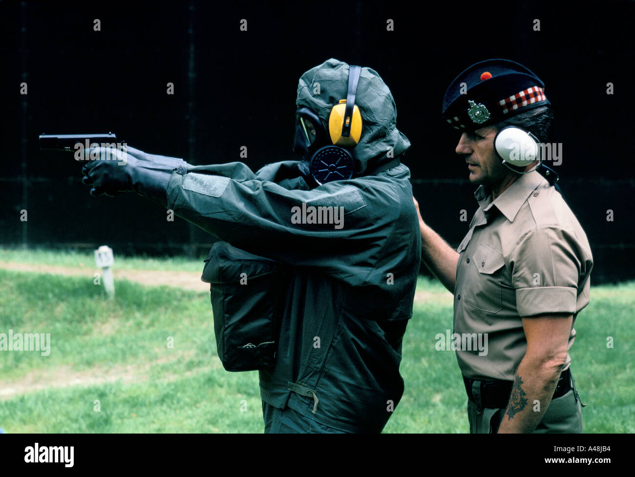 Ein Soldat Ausbildung für chemische Kriegsführung angewiesen ist wie mit Kleinwaffen während des Tragens eines atomarer und chemischer Schutz-Anzug Stockfoto