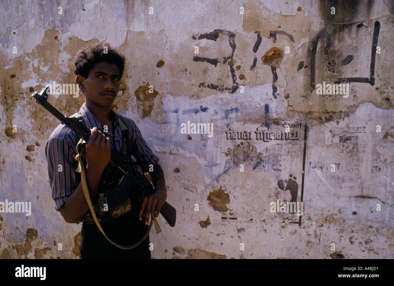 Tamil-Tiger Soldaten posiert mit seiner Kalaschnikow vor einer Wand in Jaffna Stockfoto