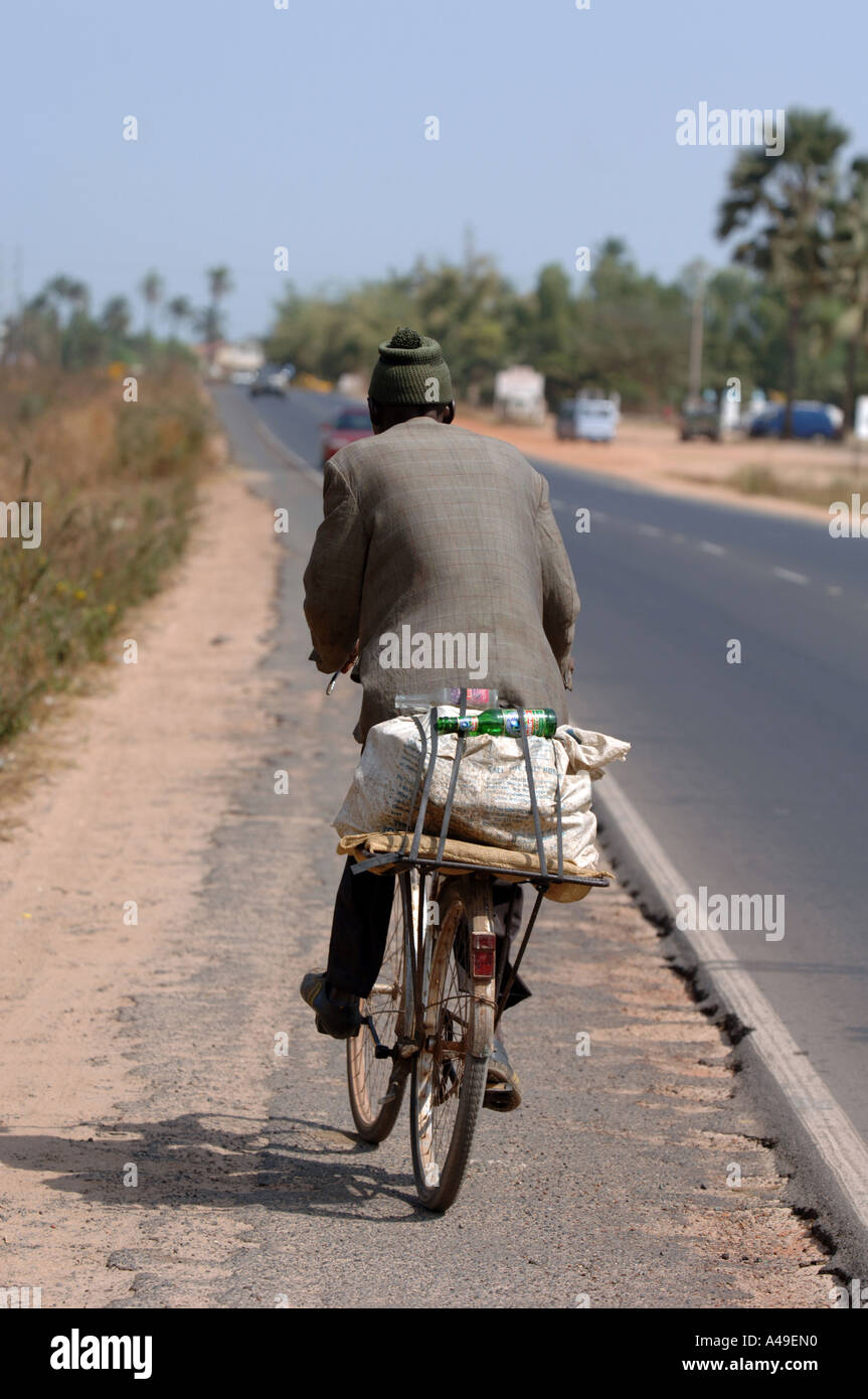Gambia, Mann Radfahren am Straßenrand Stockfoto