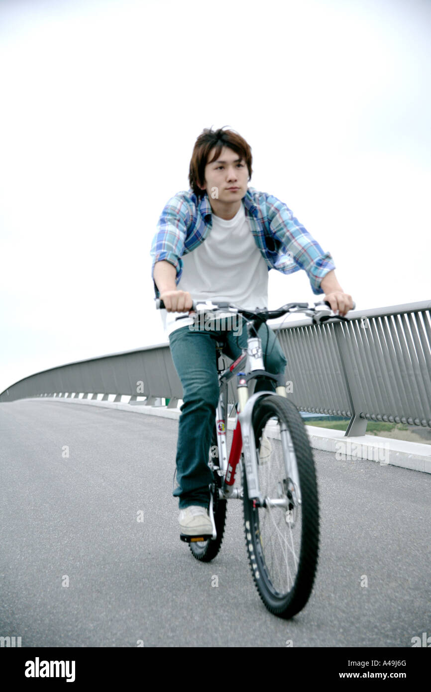 Junger Mann mit dem Fahrrad auf der Brücke Stockfoto