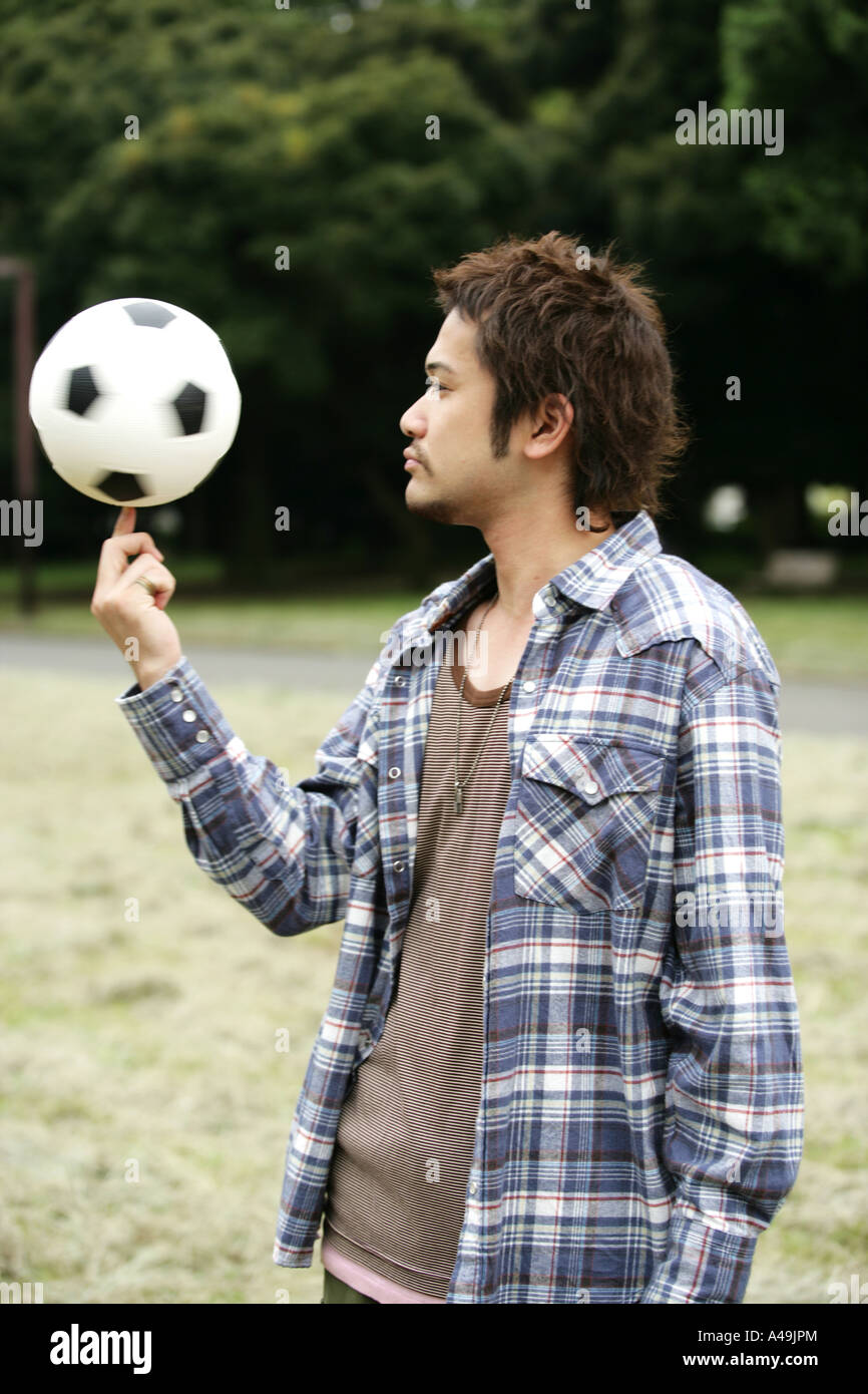 Seitenansicht eines jungen Mannes, der einen Fußball an seinem Finger drehen Stockfoto