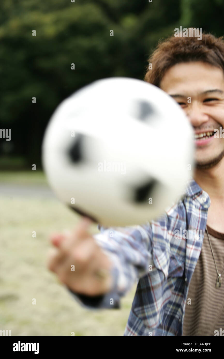 Junger Mann einen Fußball an seinem Finger drehen Stockfoto