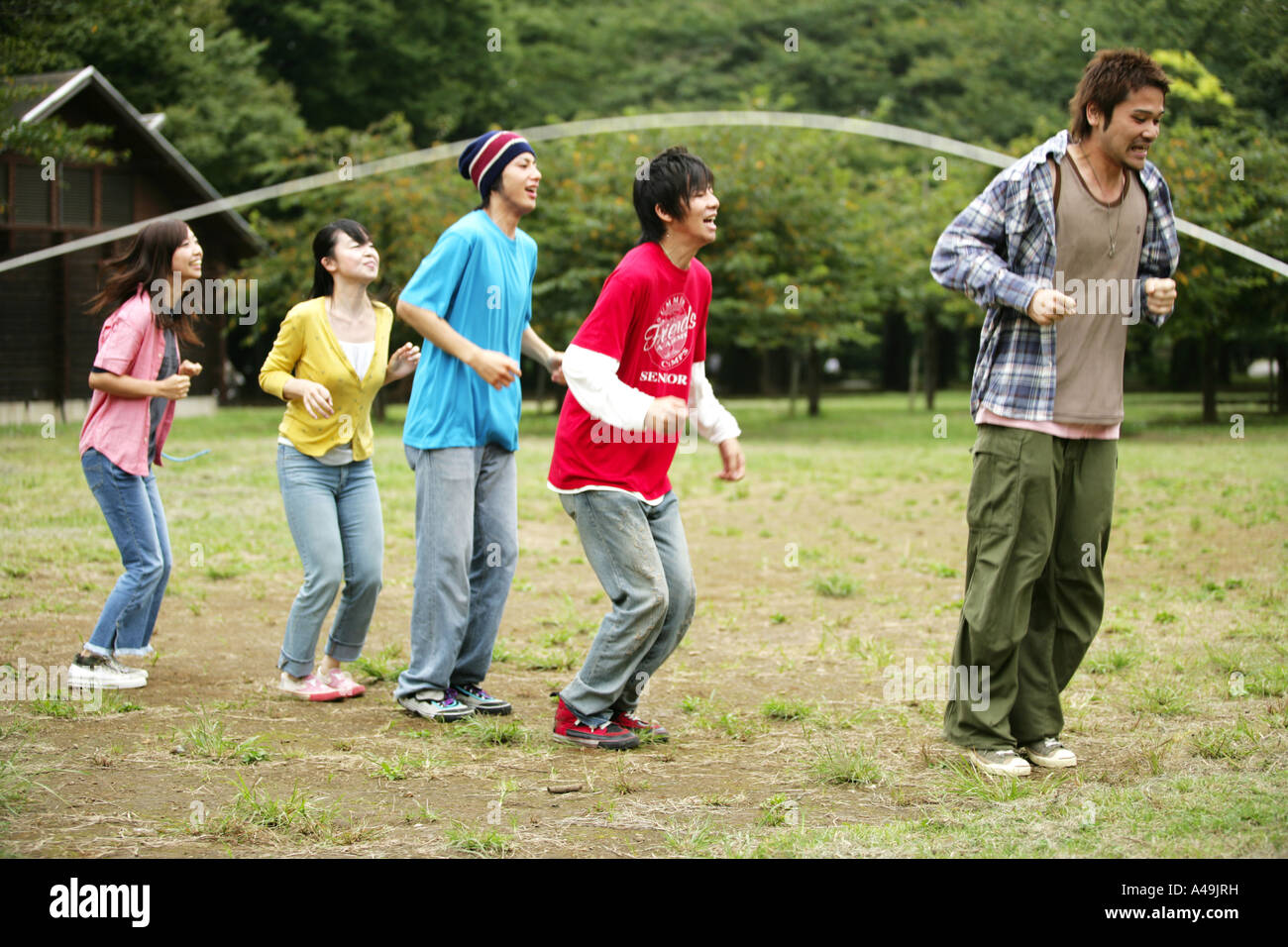 Drei junge Männer und zwei junge Frauen spielen Springseil Stockfoto