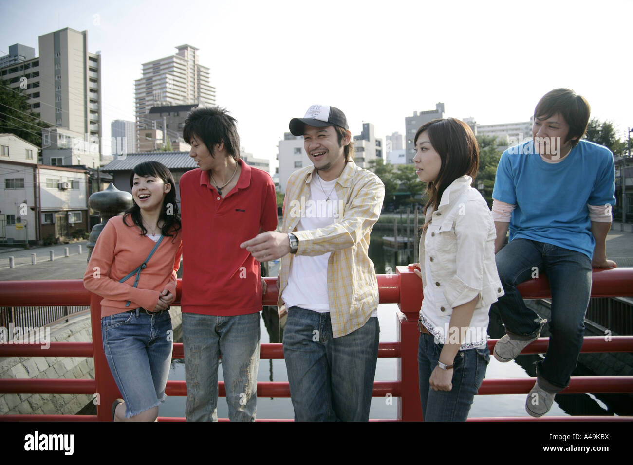 Drei junge Männer und zwei junge Frauen auf einem Geländer gelehnt und wegsehen Stockfoto