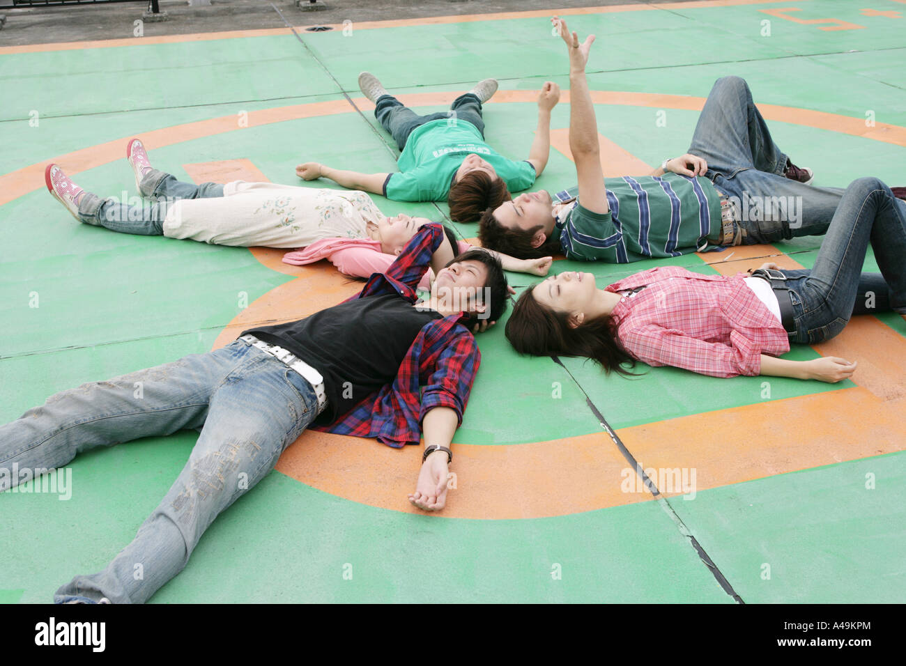 Vogelperspektive Blick auf zwei junge Frauen und drei junge Männer, die auf dem Boden liegend Stockfoto