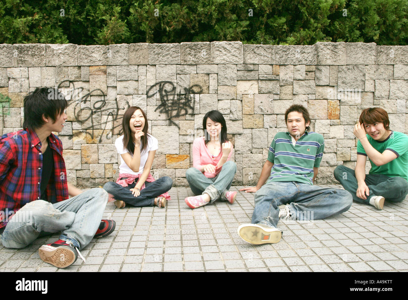 Zwei junge Frauen und drei junge Männer sitzen zusammen Stockfoto