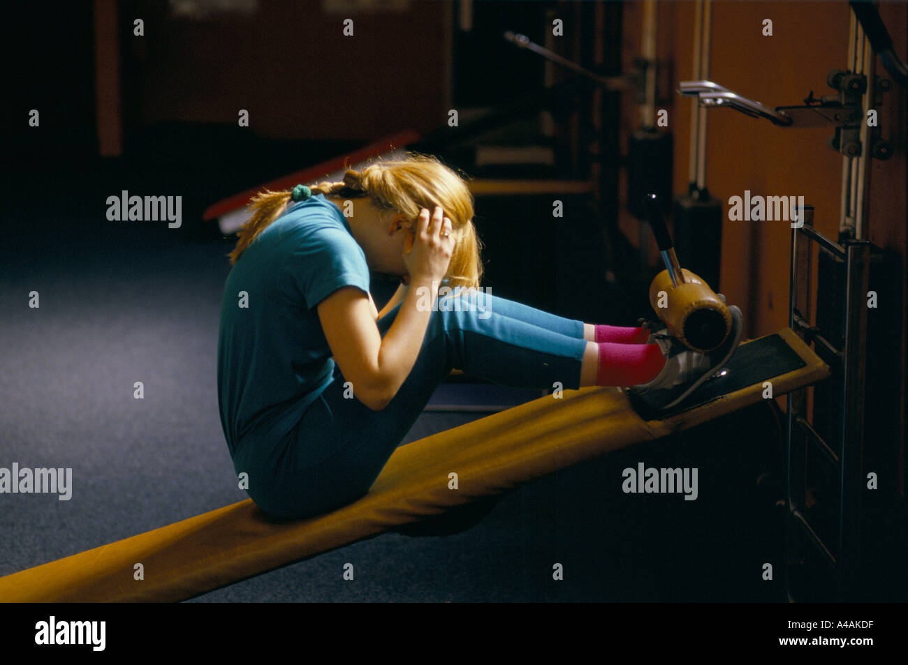 eine Frau sitzt zusammengerollt direkt auf einem Tilt Board dabei Sit Ups beim Fitness-training im Sportzentrum in hackney, London Stockfoto