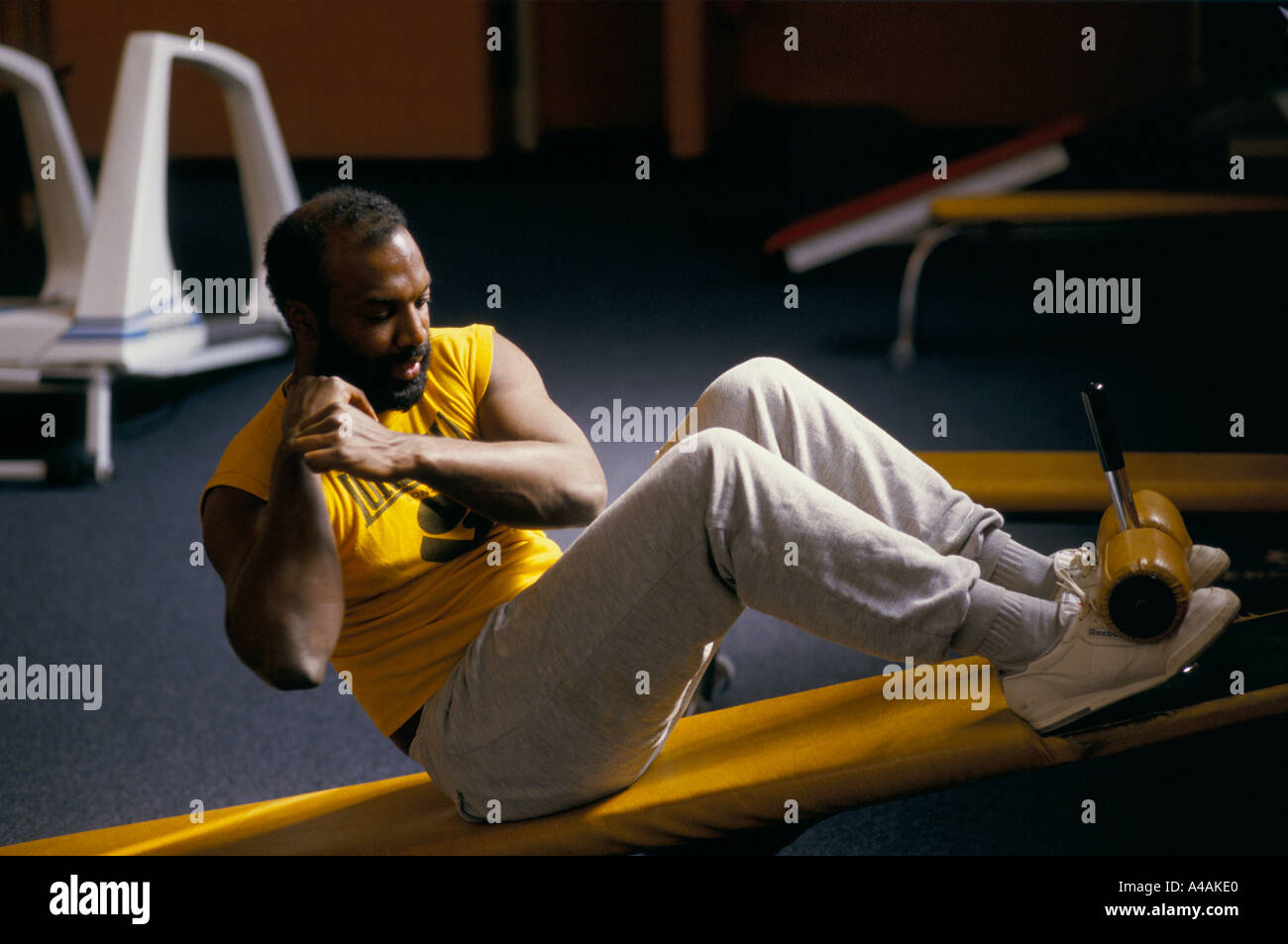 Mann tut Sit Ups auf einen Tilt Board bei einem Sportzentrum in Hackney Stockfoto