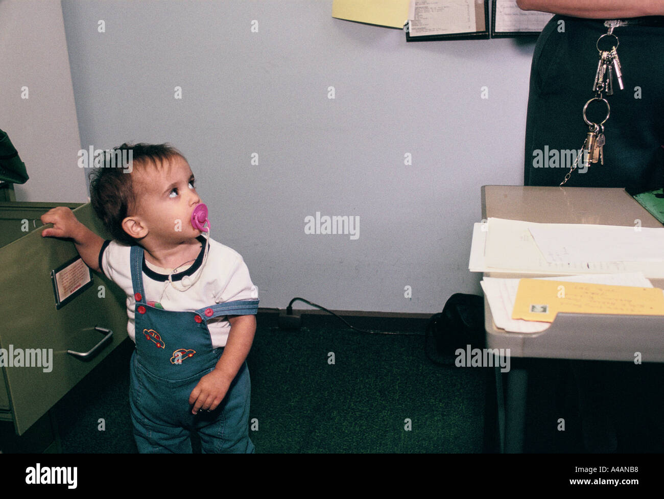 Ein Kind im Gefängnis Büro sieht in einem Gefängnis Offizier, der trägt eine Reihe von glänzenden Schlüssel. Stockfoto