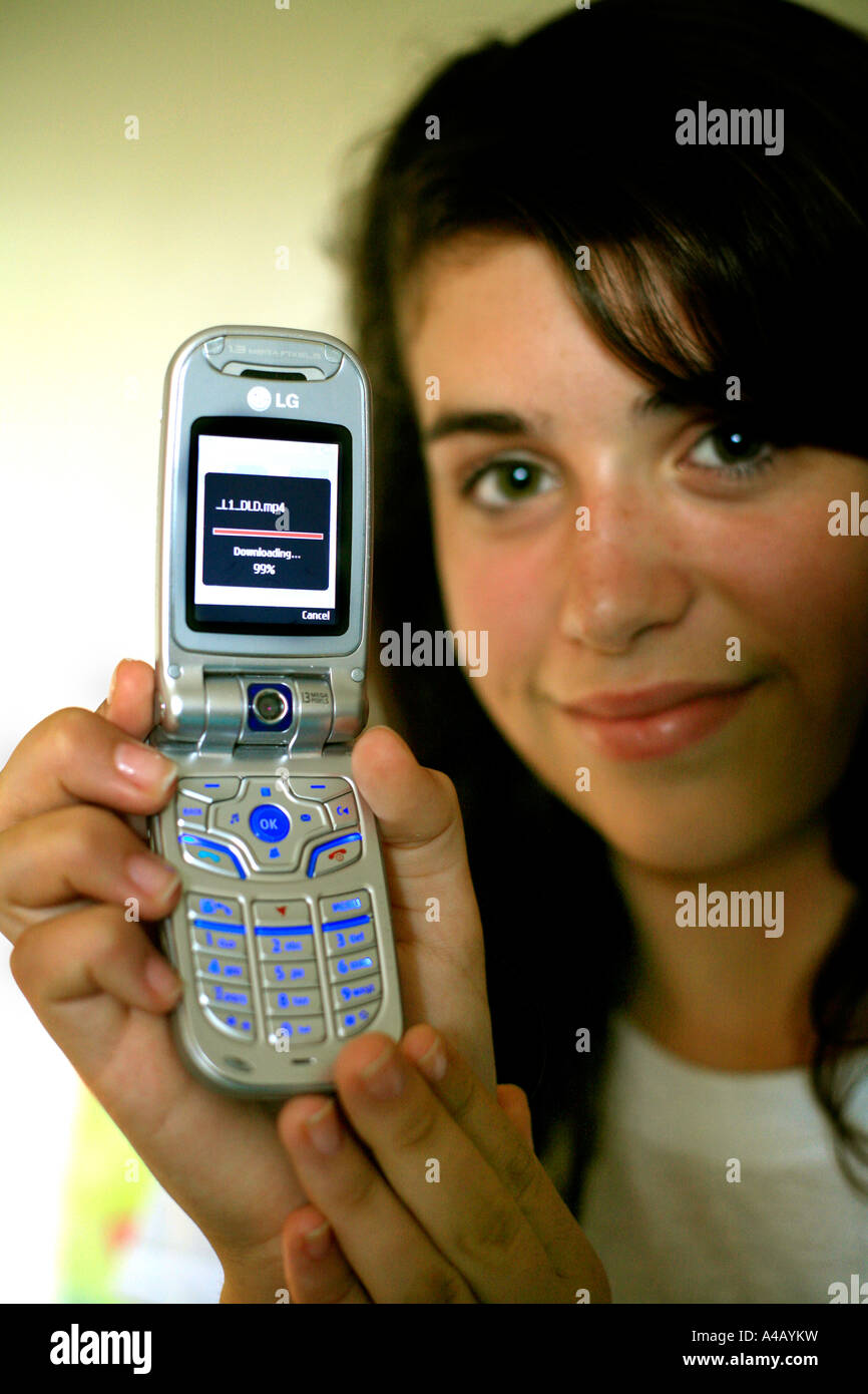 Eine teenie Girl lädt eine Musik-Video auf einem 3G in der Lage, Handy oder Handy Mobilteil Stockfoto