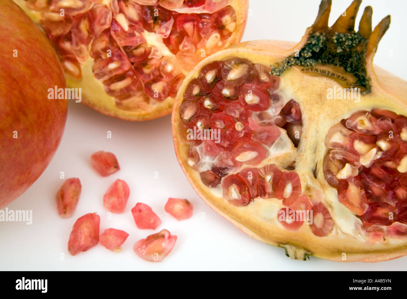Nahaufnahme von geteilten Granatäpfeln, die Samen in und zeigen Auf weißem Hintergrund entfernt Stockfoto