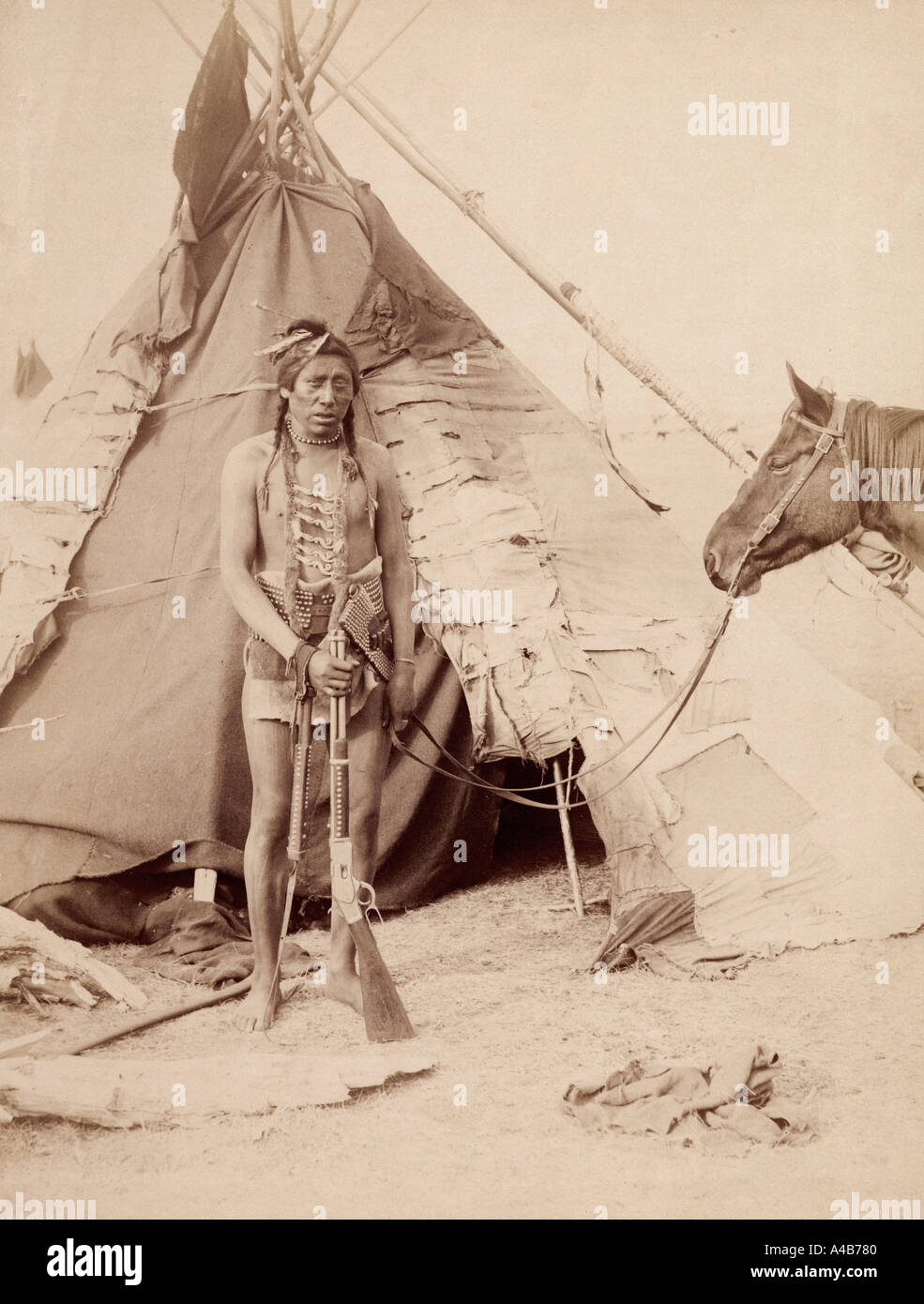 Ein Indianer steht am Eingang zu seinem Tipi mit einem Gewehr Stockfoto
