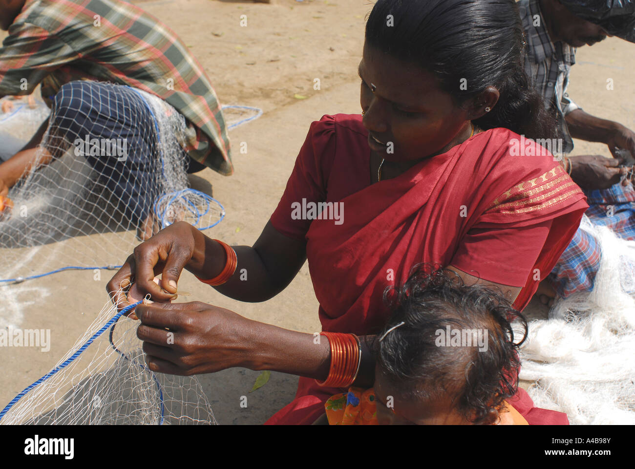 Abbildung des indischen Stammes-Fischer und Frau Fischer reparieren ihre Netze in der Nähe von Chennai Tamil Nadu, Indien Stockfoto