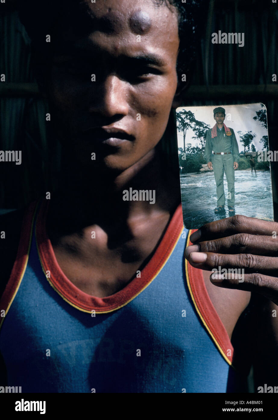 Ehemaliger Soldat der Roten Khmer, entführt von den Roten Khmer, dann floh, hält ein Foto von sich in KR-uniform Stockfoto