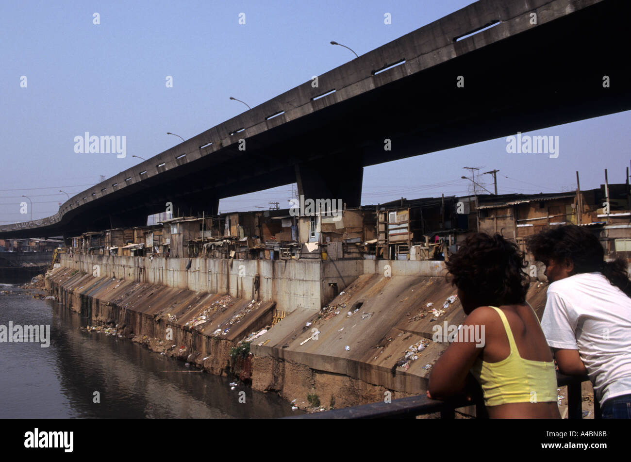Sao Paulo, Brasilien. Favela Elendsviertel vom Fluss Tiete zeigen, Verschmutzung und Abfall; zwei Mädchen. Stockfoto