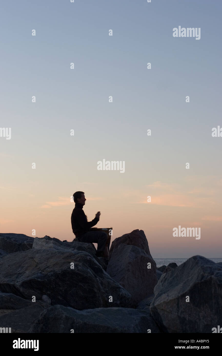 Bongo-Trommler sitzt auf den Felsen schlagen bis zum Ende der Tag des Sommers Stockfoto