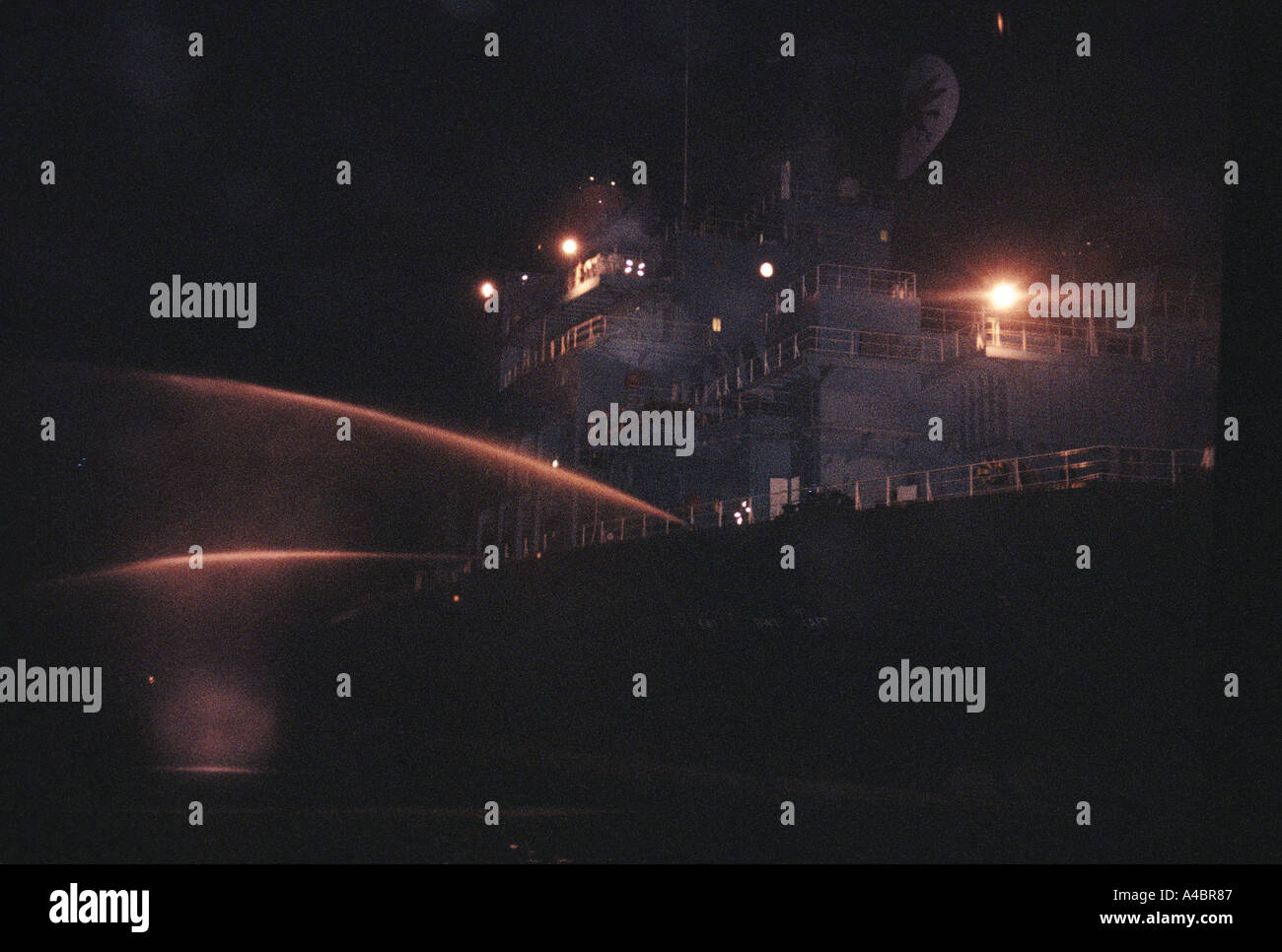 Ein Schiff segelt durch die Singapur Straits Spritzen Meerwasser aus Schläuchen aus dem Heck - eines der wenigen rechtlichen Abwehrmaßnahmen Stockfoto