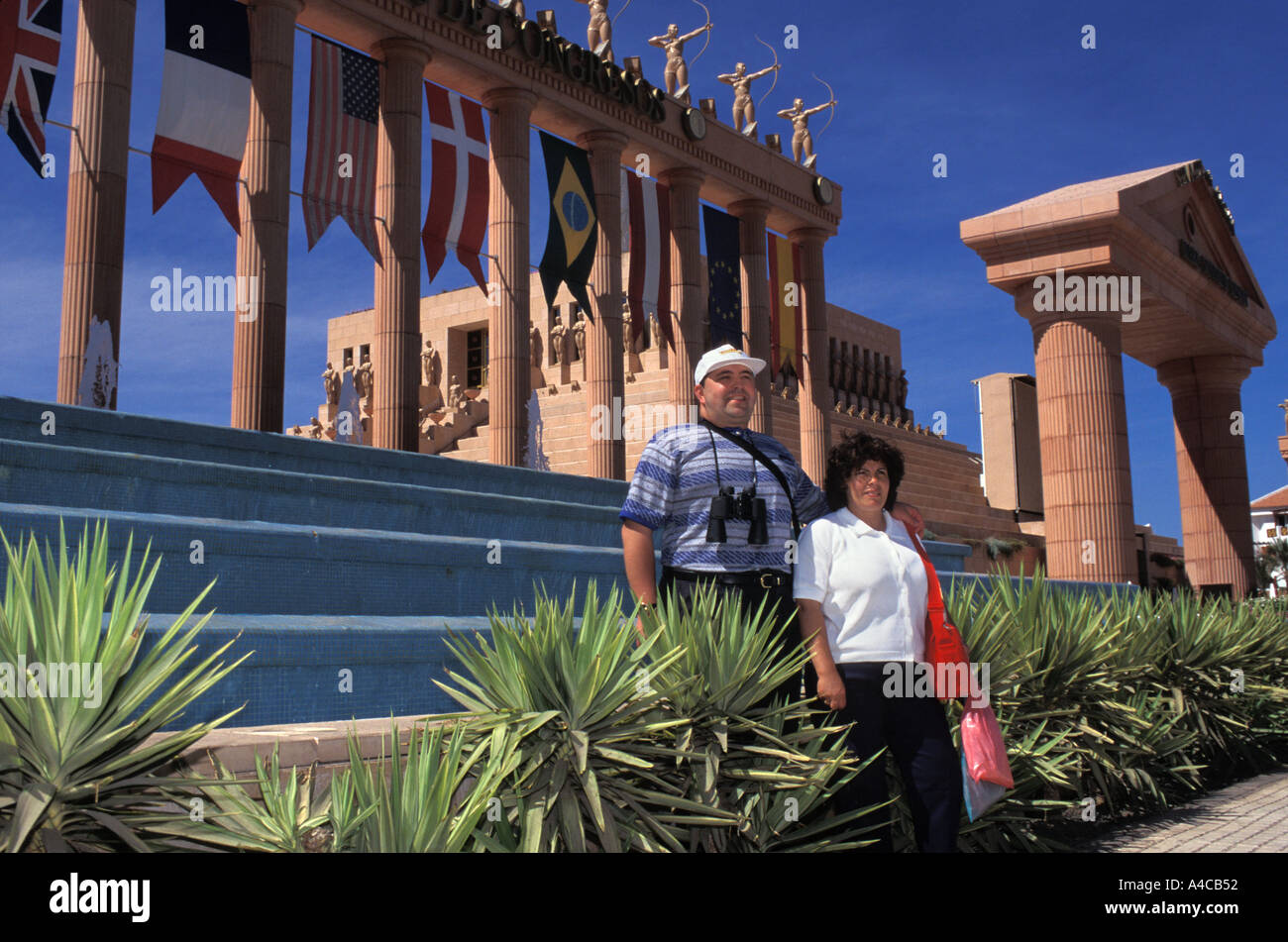 Zu verspotten Touristen posieren für ein Foto vor der römischen Hotelentwicklung in Playa de Las Americas, Teneriffa, Spanien Stockfoto
